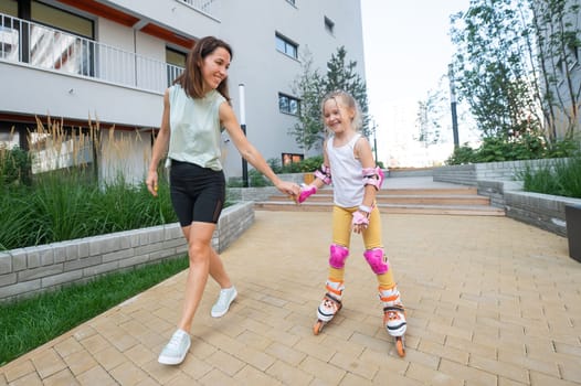 Mother helps daughter learn to roller skate