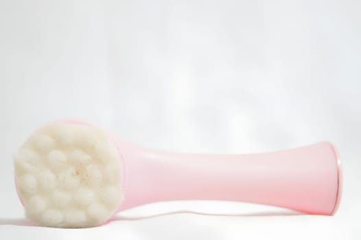 A pink brush with white bristles is laying on a white surface. High quality photo
