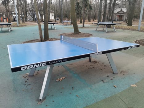 tennis table on the park area around lawn blue white metallic. sun game players, nobody, school yard. High quality photo