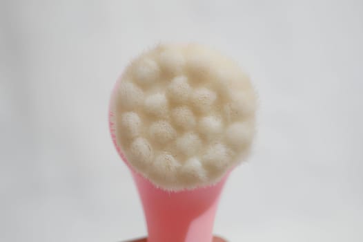 A pink brush with white bristles is shown in a close up. High quality photo