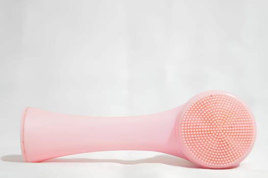 A pink brush with a white handle sits on a white surface. High quality photo