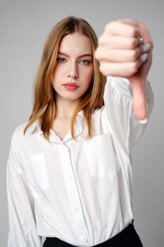 Young Woman in White Shirt Pointing Finger Down Dislike against gray background