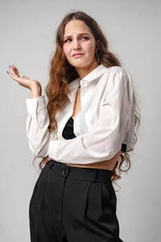 A woman stands wearing a white shirt and black pants. She is posing for the camera in a casual outfit, exuding confidence and style.