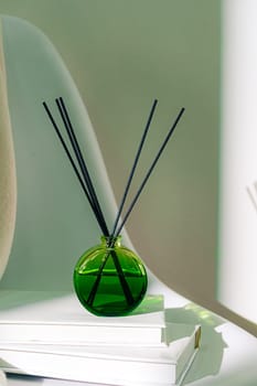 Liquid home perfume in glass diffuser with sticks on chair close up