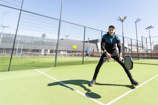 Young padel player trains by catching high balls. High quality photo