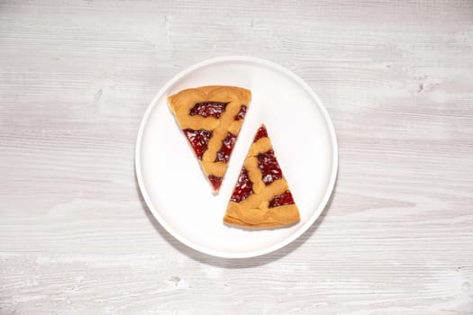 Two pieces of cherry pie on a white wooden table.