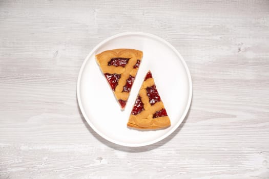 Two pieces of cherry pie on a white wooden table.