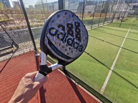 Ukraine Kyiv, April 11 2024: Padel racket adidas and padel ball on a green court . High quality photo