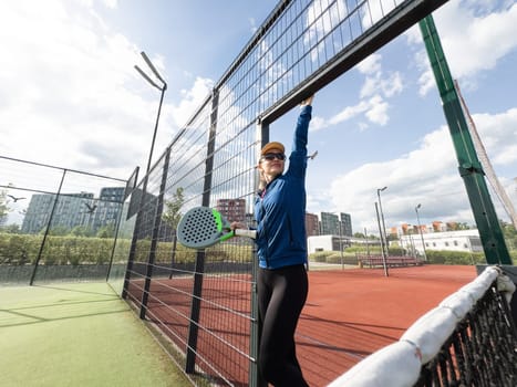 Woman playing padel in a green grass padel court behind the net. High quality photo