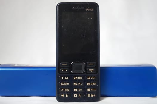 A black flip phone sits on a blue object. High quality photo