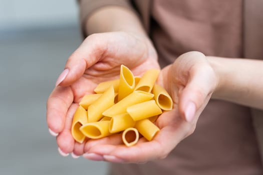 Mostaccioli pasta in the palm of a hand isolated over a white background. High quality photo