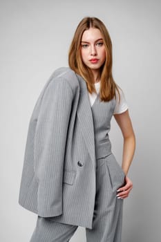 Woman in Gray Suit and White Shirt posing in studio on gray background