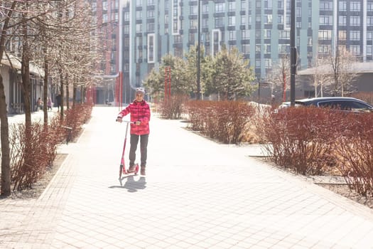 Little cute girl riding a scooter on a path in the park. High quality photo