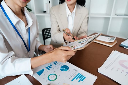 Collaborative business woman meeting hands analyzing financial charts and graphs on office desk for strategic planning.