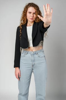 Woman With Curly Hair Holding Hand Up in Studio