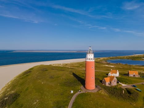 An imposing lighthouse stands tall against the backdrop of a calm beach, offering a beacon of hope and guidance to passing ships. The iconic red lighthouse of Texel Netherlands