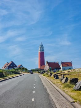 A scenic road winds towards a majestic lighthouse standing tall in the background, framing the picturesque landscape with its beacon of hope.