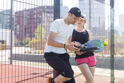 Ukraine Kyiv, April 02 2024. Young woman and man talking to each other after playing padel, walking along the net together. High quality photo