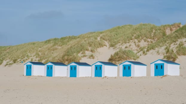 A colorful row of beach huts standing proudly on a sandy beach in Texel, Netherlands, basking in the suns glow. De Koog beach Texel