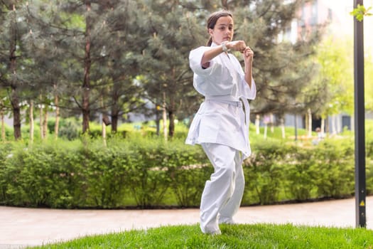 Young active girl wearing in white kimono with white belt performing martial arts kick skills. sporty karate woman improving fight technique on Chinese bridge. concept of sport. High quality photo