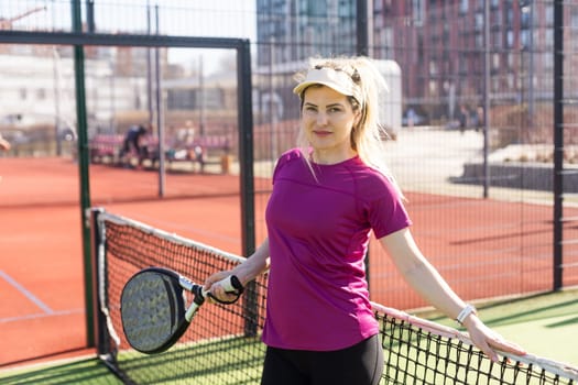 Young sporty woman playing padel game in court on sunny day. High quality photo