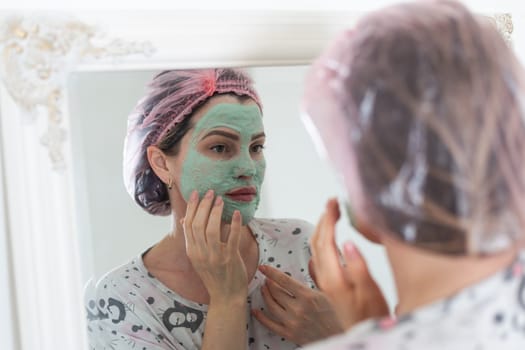 Self care: a woman applying clay mask to her face. High quality photo