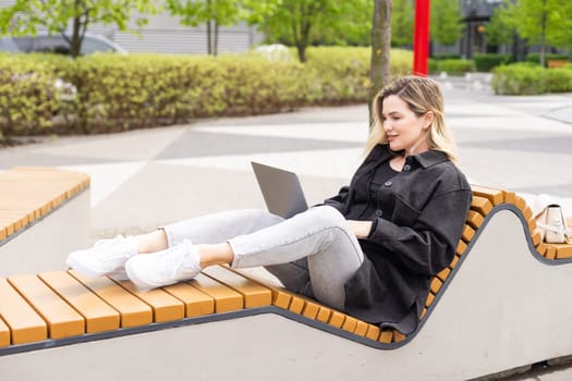 Young beautiful business woman sitting on a bench in the sunny city. High quality photo