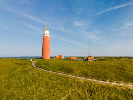 A majestic lighthouse stands tall on a grassy field, casting a watchful eye over the Texel landscape below.