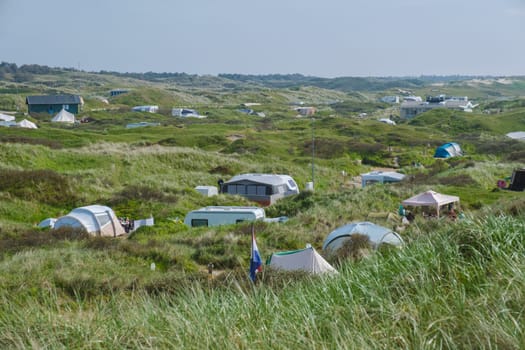 A group of tents nestled on a lush grassy hillside on the picturesque island of Texel in the Netherlands, offering a peaceful and idyllic retreat for outdoor adventurers.