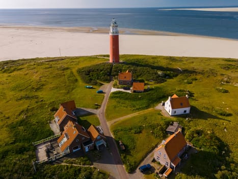 An aerial view of a majestic lighthouse standing tall on the sandy beach, overlooking the vast ocean with its beacon shining bright.