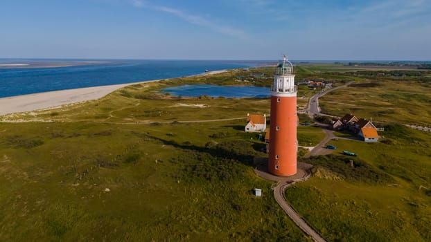 A majestic lighthouse stands tall by the beach, casting its light over the vast ocean, guiding ships safely to shore.