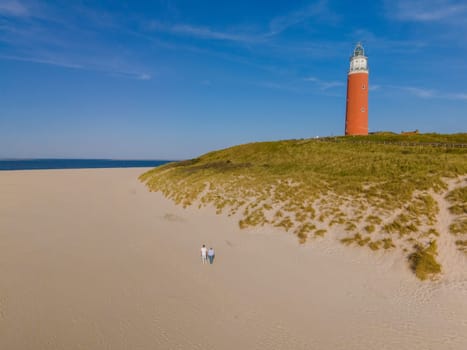 A stunning aerial view of a towering lighthouse standing proudly on a pristine sandy beach in Texel, Netherlands.