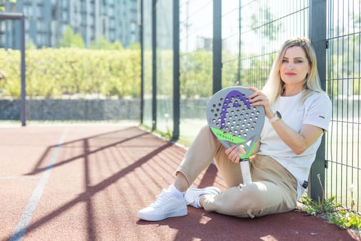 Ukraine Kyiv, May 03 2024. Portrait of smiling woman with padel tennis racket head at court. High quality photo