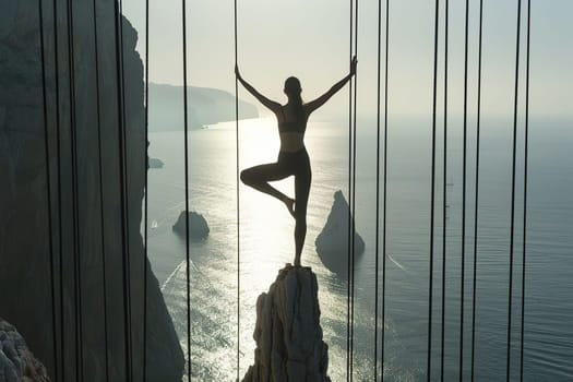 A slender girl in an asana on a rock overlooking the ocean.