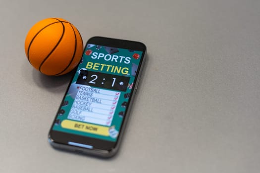 Sports betting website in a mobile phone screen, ball, money. High quality photo