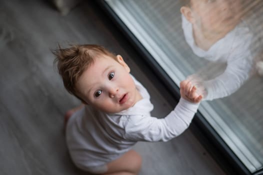 Baby boy standing by the patio window