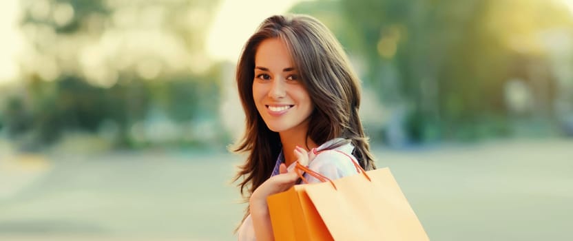 Portrait of happy brunette young woman with shopping bags walking in the city