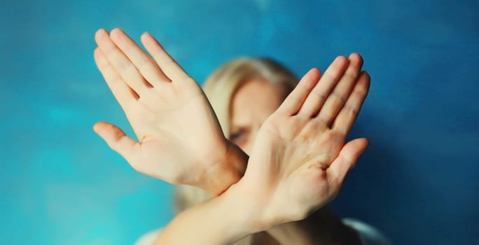 Upset young woman shows stop, no or enough sign with palm of hand, refusal gesture, domestic violence