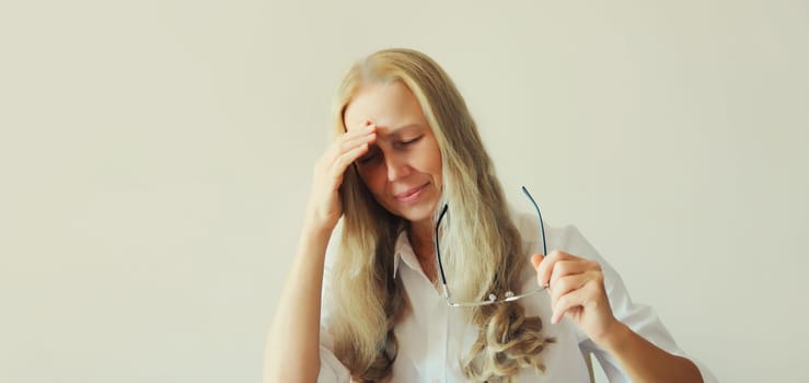 Exhausted tired caucasian mature woman employee with headache, stress, fatigue, temples pain, suffers from migraine, tension in the head in the office