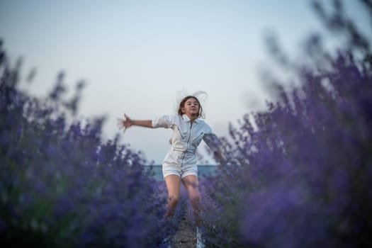 Lavender field happy girl in white dress with a scythe runs through a lilac field of lavender. Aromatherapy travel.