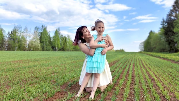 Happy mother and daughter enjoying rest, playing and fun on nature in green field. Woman and girl resting outdoors in summer or spring day