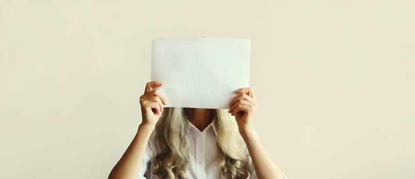 Woman showing and holding white blank sheet of paper document for advertising text blank copy space on studio background