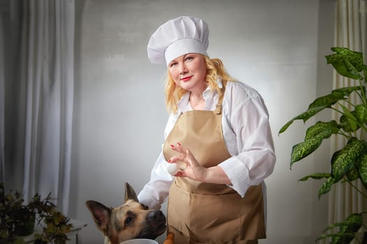 Fat funny female cook in a hat and apron in the kitchen with big shepherd dog. Good cooking, body positive, pet