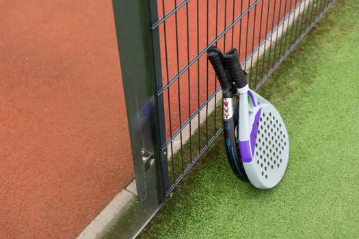 Padel racket and padel ball on a green court in the sunset. High quality photo