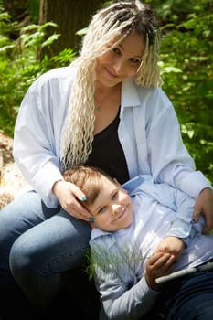 Funny mother with dreadlocks and fat boy happy walking in the forest on a sunny summer day