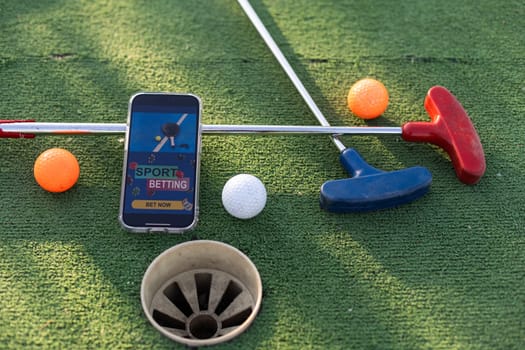 golf equipment on the green lawn. mini golf sports betting on a smartphone. High quality photo