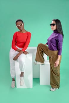 Two women pose on a color background. High quality photo
