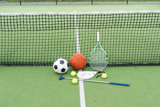 football soccer ball basketball tennis ball and racket laid on grass at sunset. High quality photo
