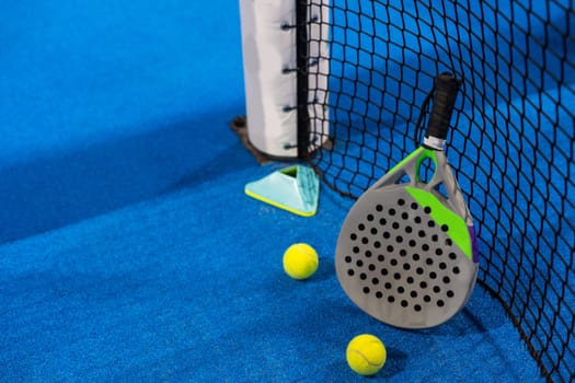 Twoo balls next to the net of a blue paddle tennis court. Sport healthy concept. High quality photo