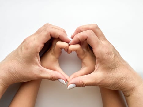 Close up of middle age woman and childs hands forming heart shape on white background. Family love and connection concept. Design for healthcare, wellness, and family care poster. High quality photo